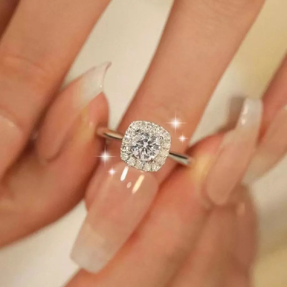 Elegant moissanite and sterling silver ring with cushion-cut center stone and halo.
