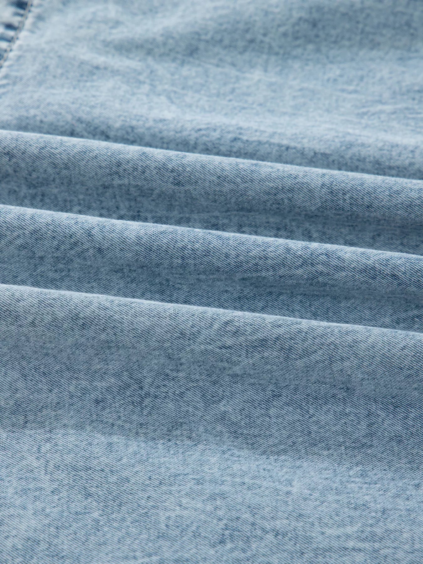 Tiered denim overall dress in light blue cotton with a textured weave.