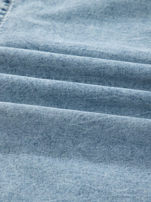 Tiered denim overall dress in light blue cotton with a textured weave.