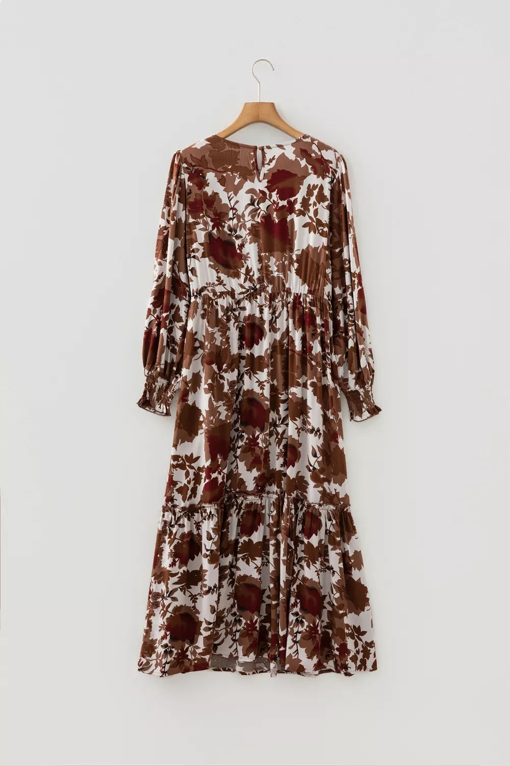 Maxi dress with brown and beige floral print, billowy sleeves, and tiered skirt.