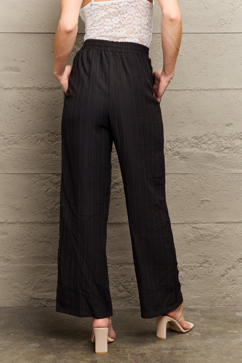 Black ribbed drawstring palazzo trousers with a wide leg and pockets.