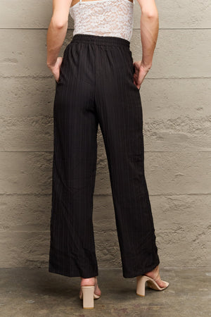 Black ribbed drawstring palazzo trousers with a wide leg and pockets.