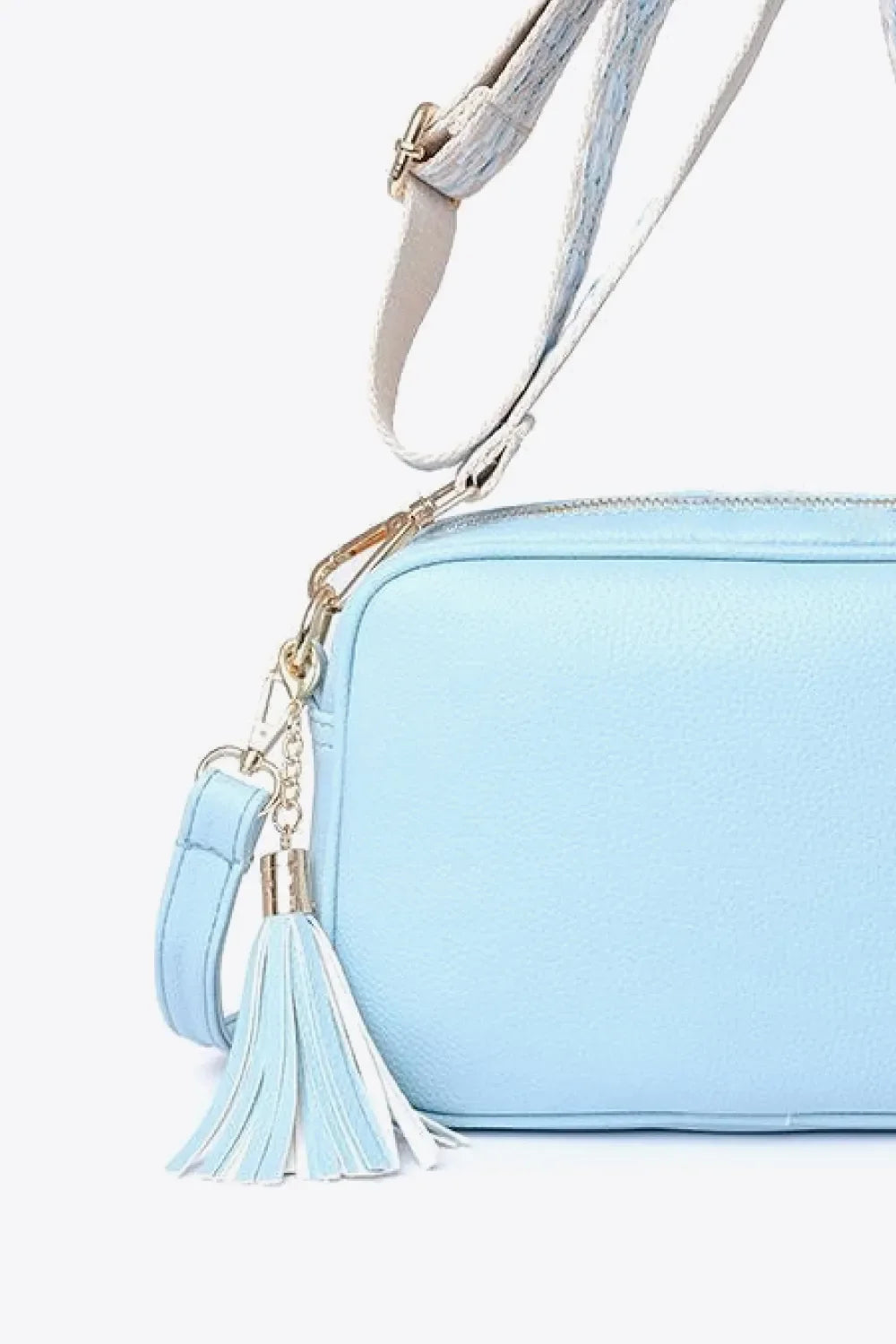 Sky blue textured crossbody bag with tassel detail and adjustable strap.