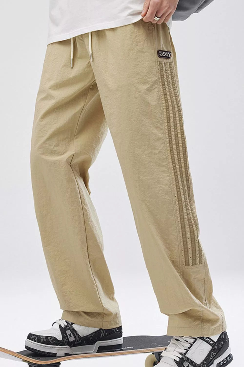 Khaki casual drawstring sweatpants with side stripes and a logo patch.