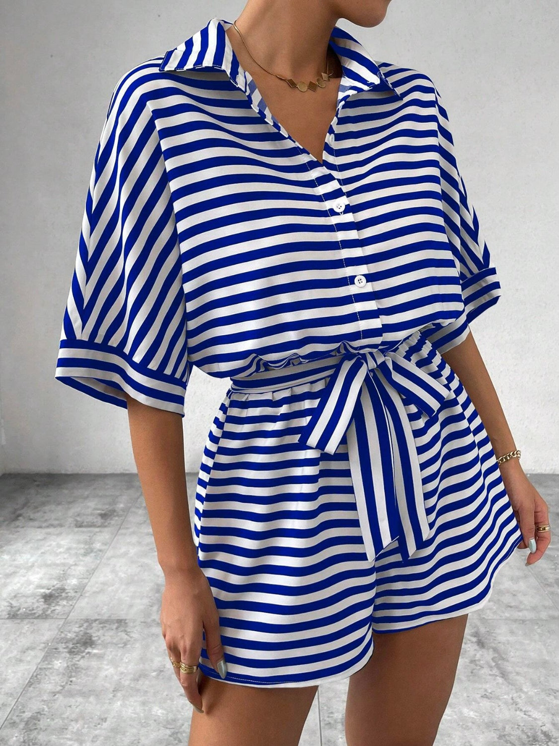 Royal blue and white striped button-front romper with short sleeves and self-tie belt.