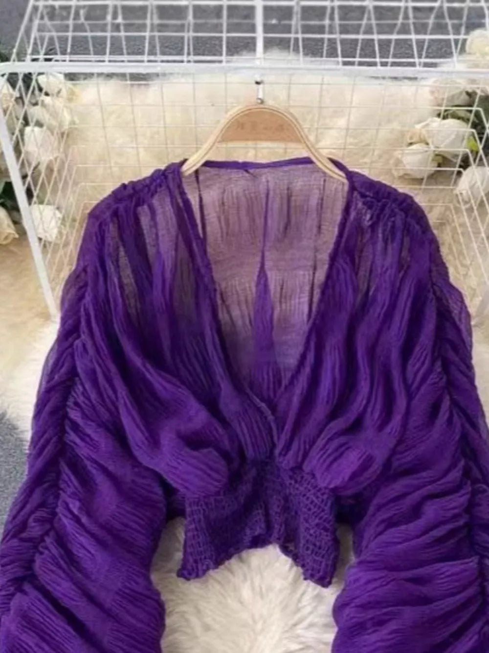 Purple ruched sleeve blouse with deep V-neck and textured bodice.