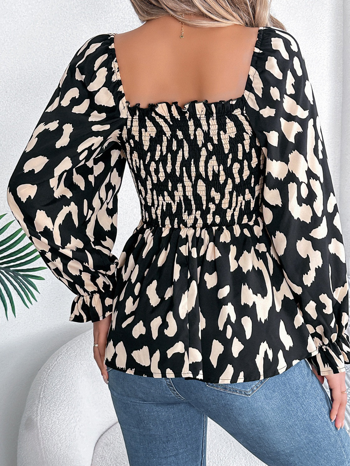 Black leopard print square neck blouse with smocked bodice and ruffled cuffs.