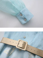 Light blue midi dress with butterfly print, cinched waist belt, and buttoned cuff detail.