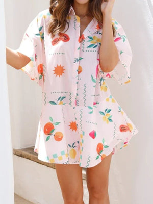 Blush pink romper with a fruit and sun print, short sleeves, and buttoned front.