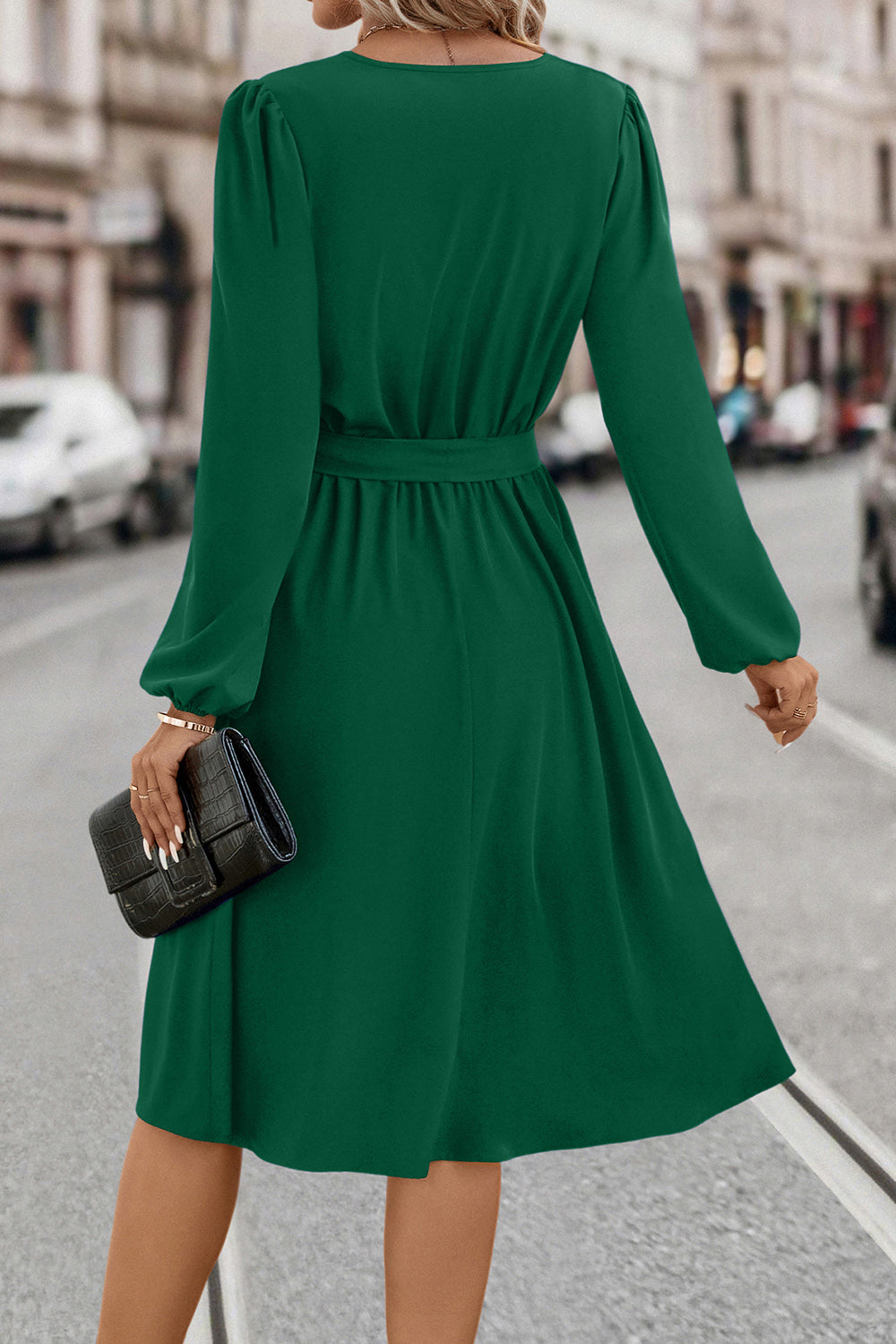 Emerald green midi dress with poet sleeves, belted waist, and a flowing skirt.