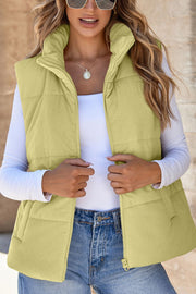 Corduroy padded vest in sage with a high collar and zip front, styled with a white long-sleeve top.