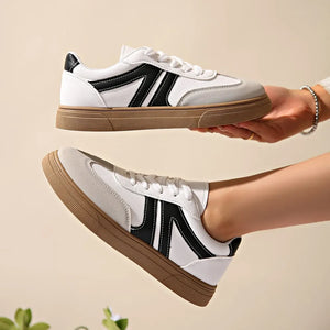 White and black suede panel sneakers with brown soles.