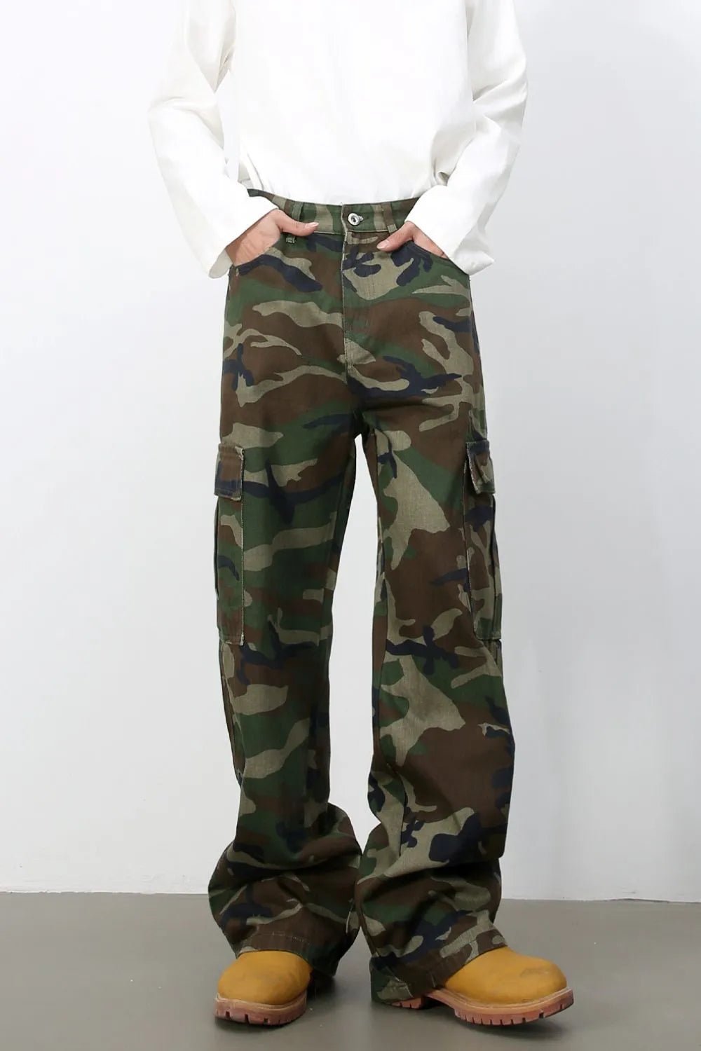 Wide-leg camo cargo pants in green camouflage pattern, 100% cotton, with multiple pockets.