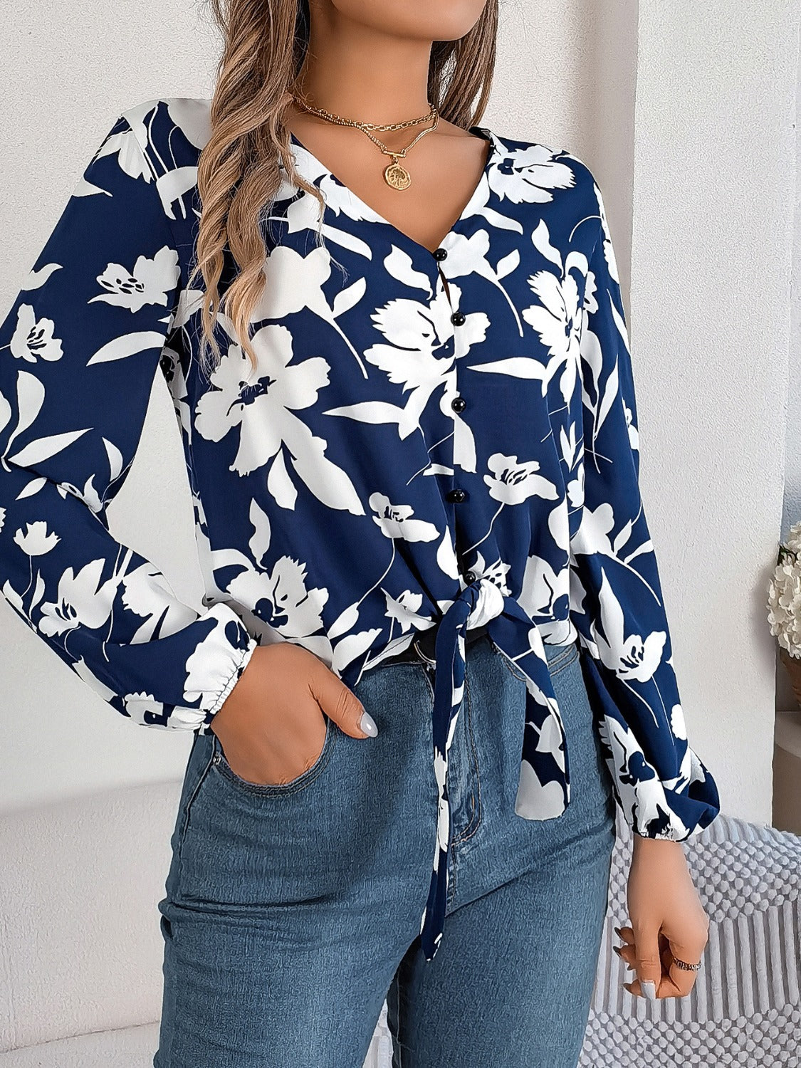 Navy floral knot-front blouse with ruffled cuffs and button detail.