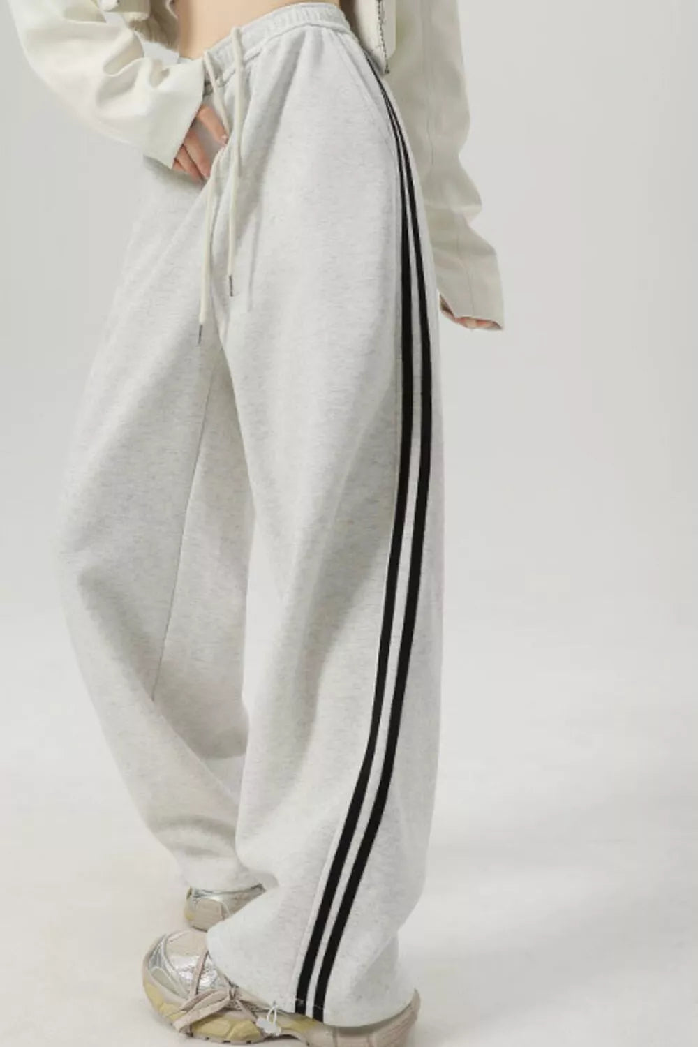 Light gray wide-leg sweatpants with drawstring and black side stripes.