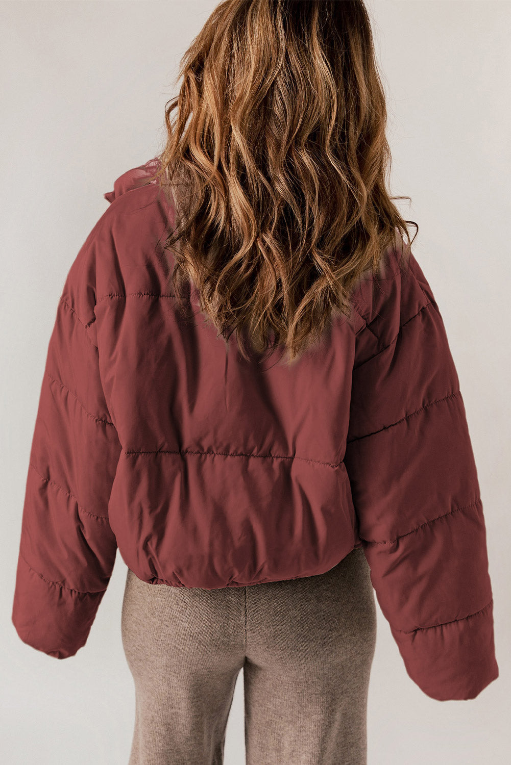 Cropped puffer jacket in brick red with a hooded collar and horizontal quilting.