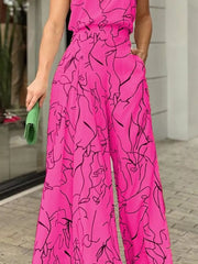 Hot pink halter neck romper with abstract face print and wide legs.