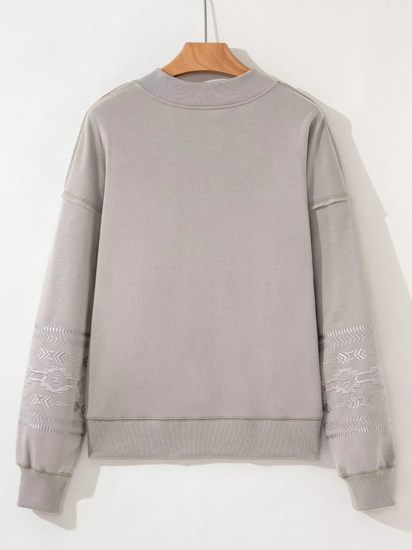 Gray sweatshirt with Aztec embroidery on sleeves and crew neck.