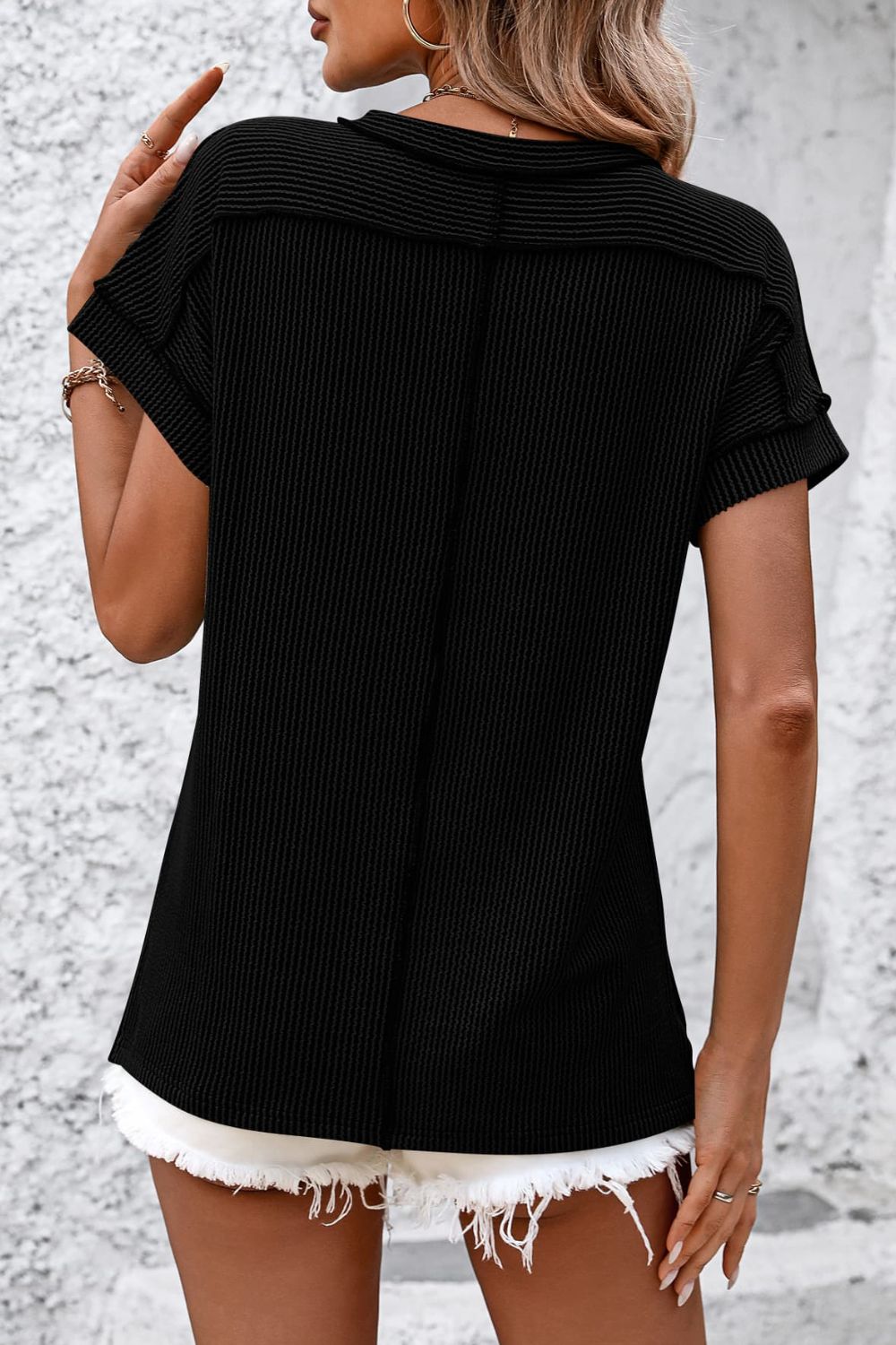 Black vertical ribbed tee with short sleeves and split hem detail.