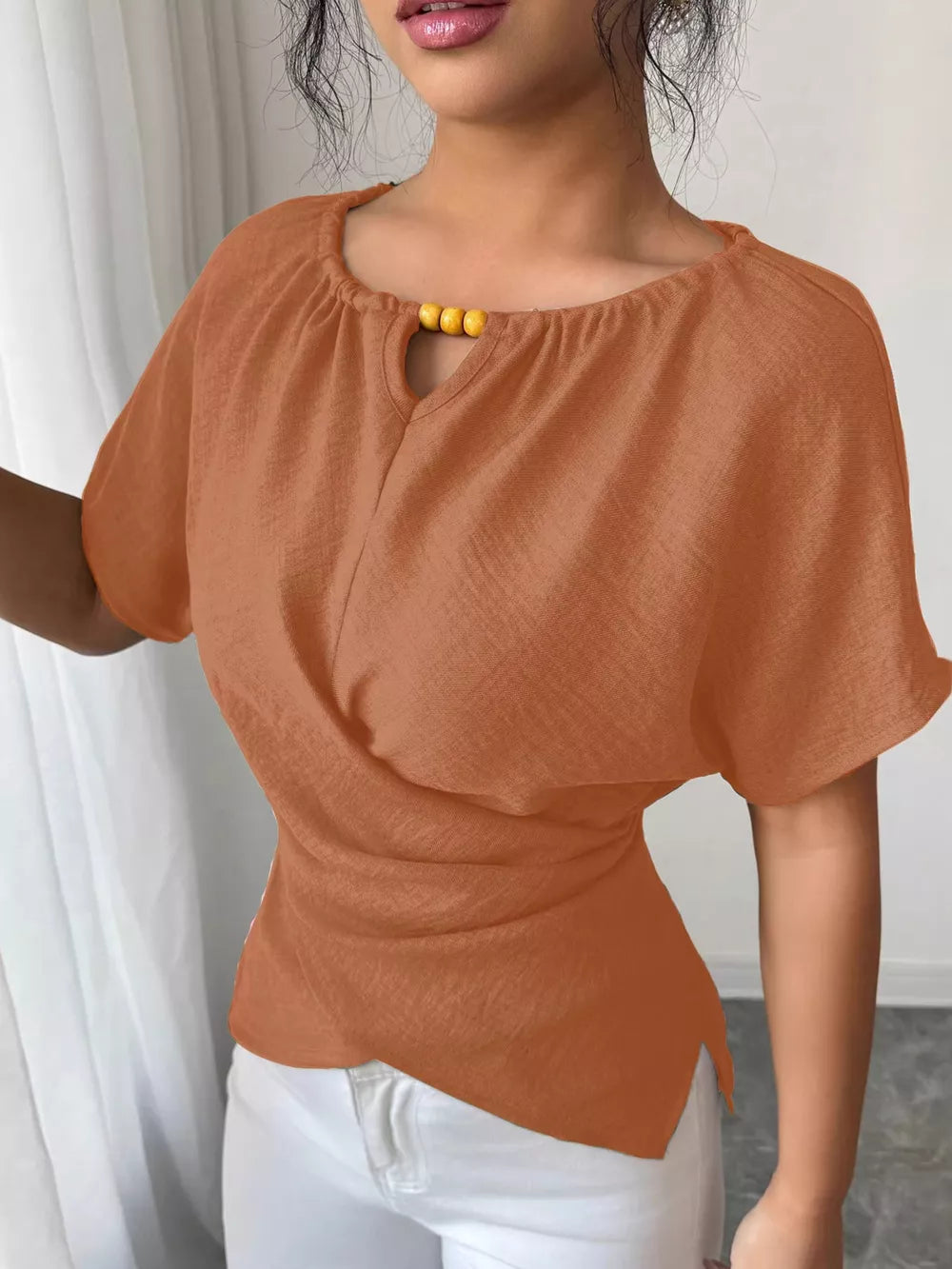 Orange short sleeve maternity blouse with beaded keyhole neckline and dolman sleeves.