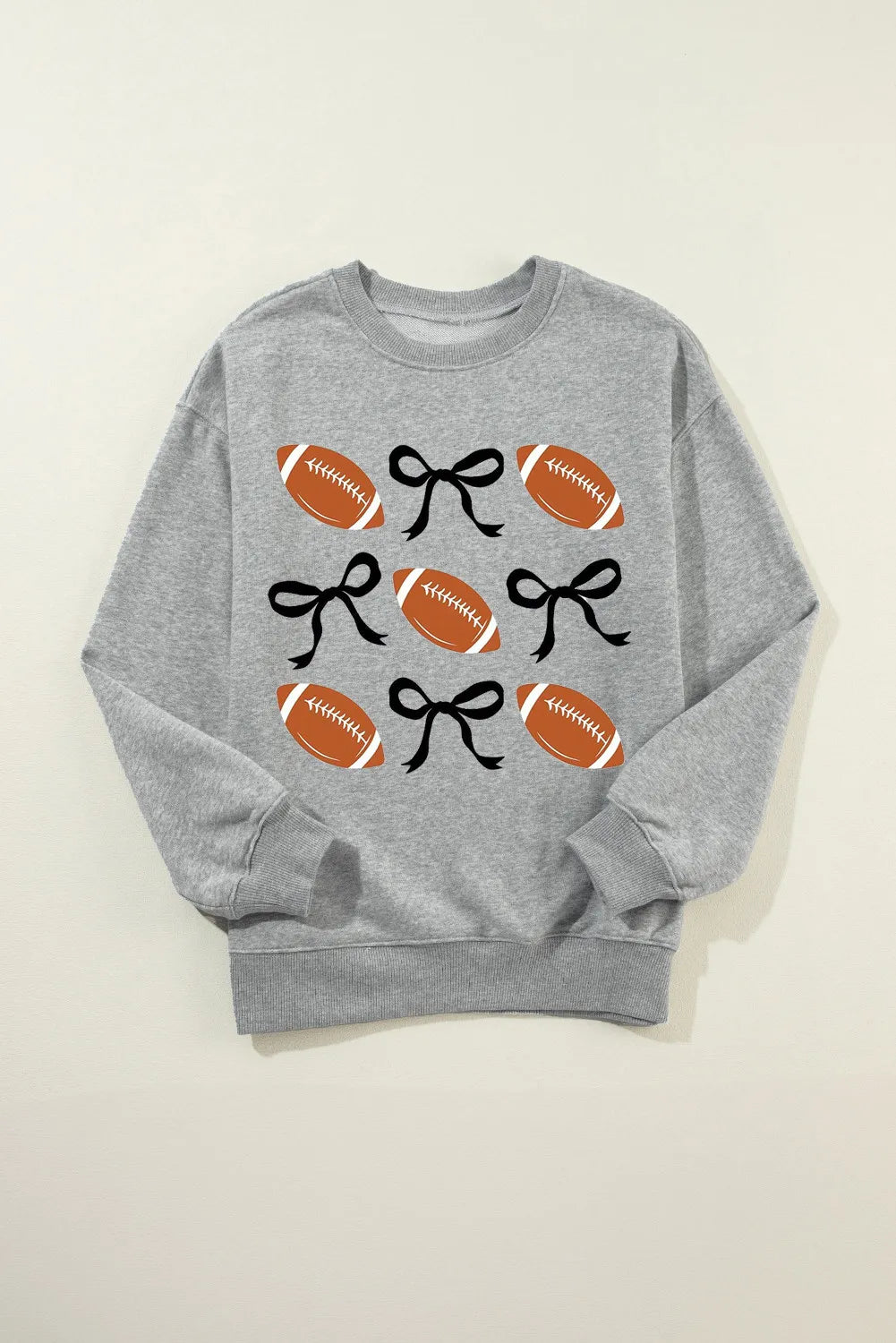 Gray sweatshirt with a grid pattern of footballs and black bows.