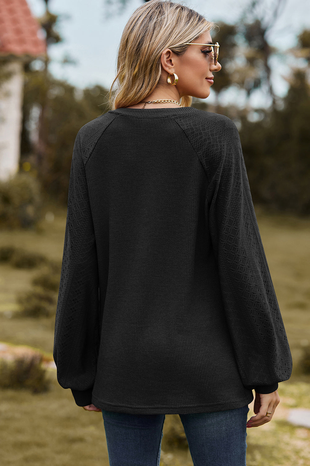 Black waffle knit raglan top with textured sleeves and V-neck.