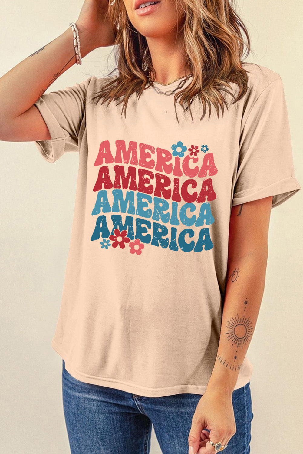 Tan t-shirt with stacked "America" graphic in red, white, and blue with floral accents.