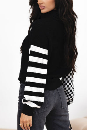 Black knit turtleneck sweater with checkerboard and stripe sleeves