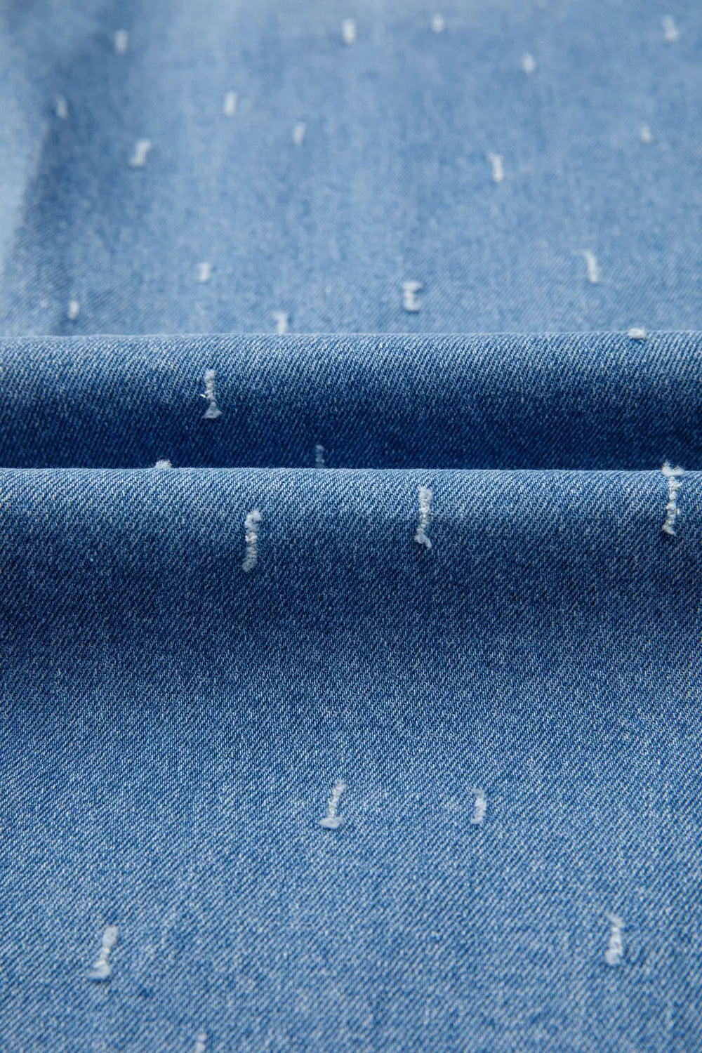 Blue denim jeans with distressed details and a raw hem.