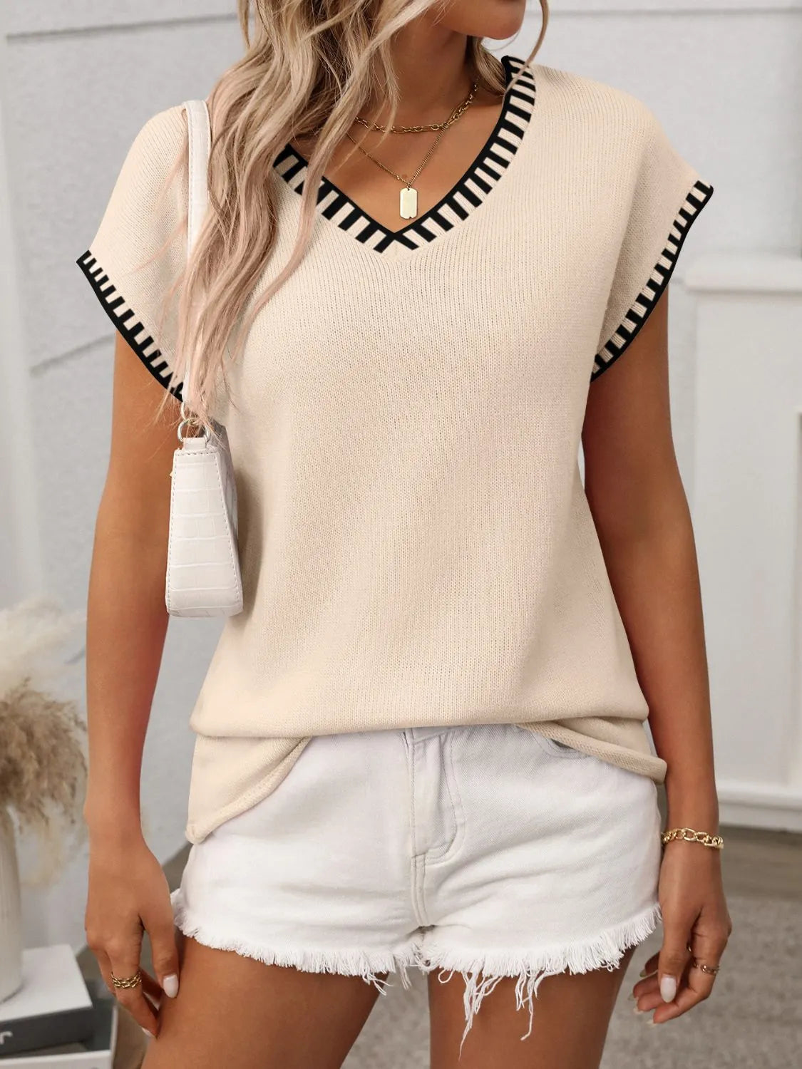 Tan knit v-neck sweater top with black striped trim on neckline and sleeves