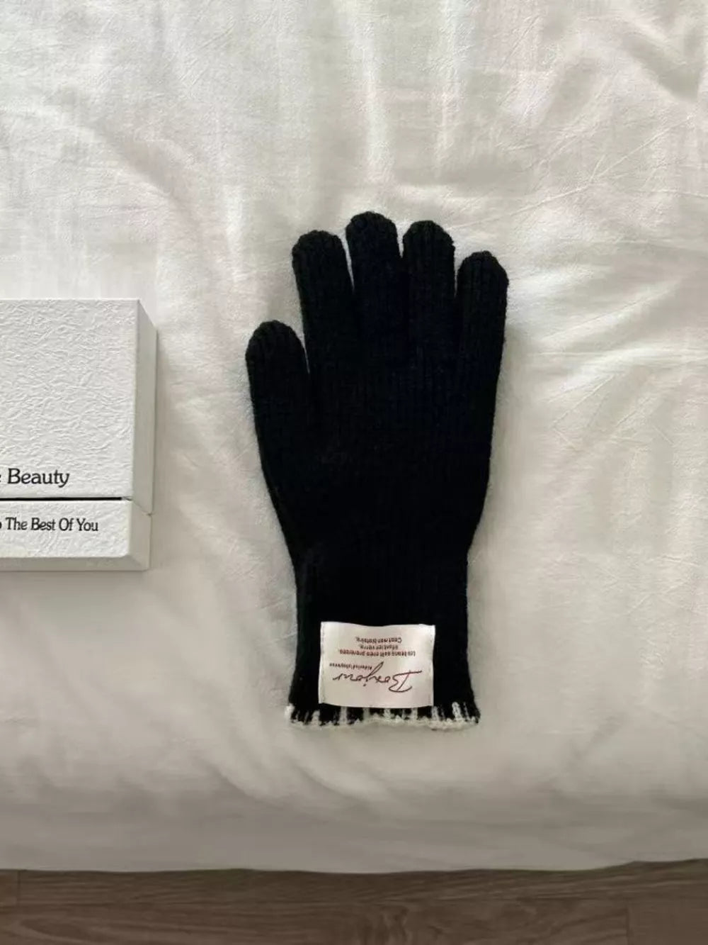 Black ribbed knit gloves with a scalloped cuff and a white label.