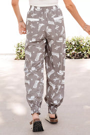 Grey cotton joggers with white western print, drawstring waist, elastic cuffs, and white pocket details.