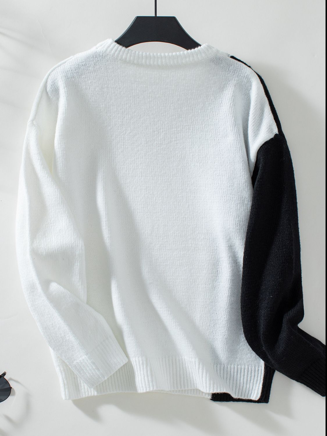 Colorblock knit sweater in white with black raglan sleeves and crewneck.