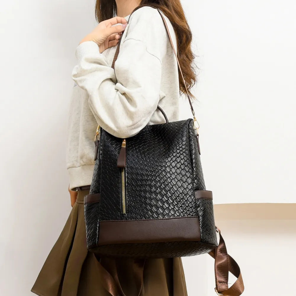 Black woven faux leather convertible backpack with brown trim and gold zipper.