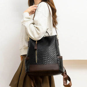 Black woven faux leather convertible backpack with brown trim and gold zipper.