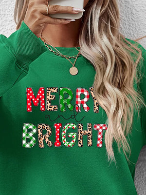Green crewneck sweatshirt with "Merry and Bright" graphic in festive patterns.
