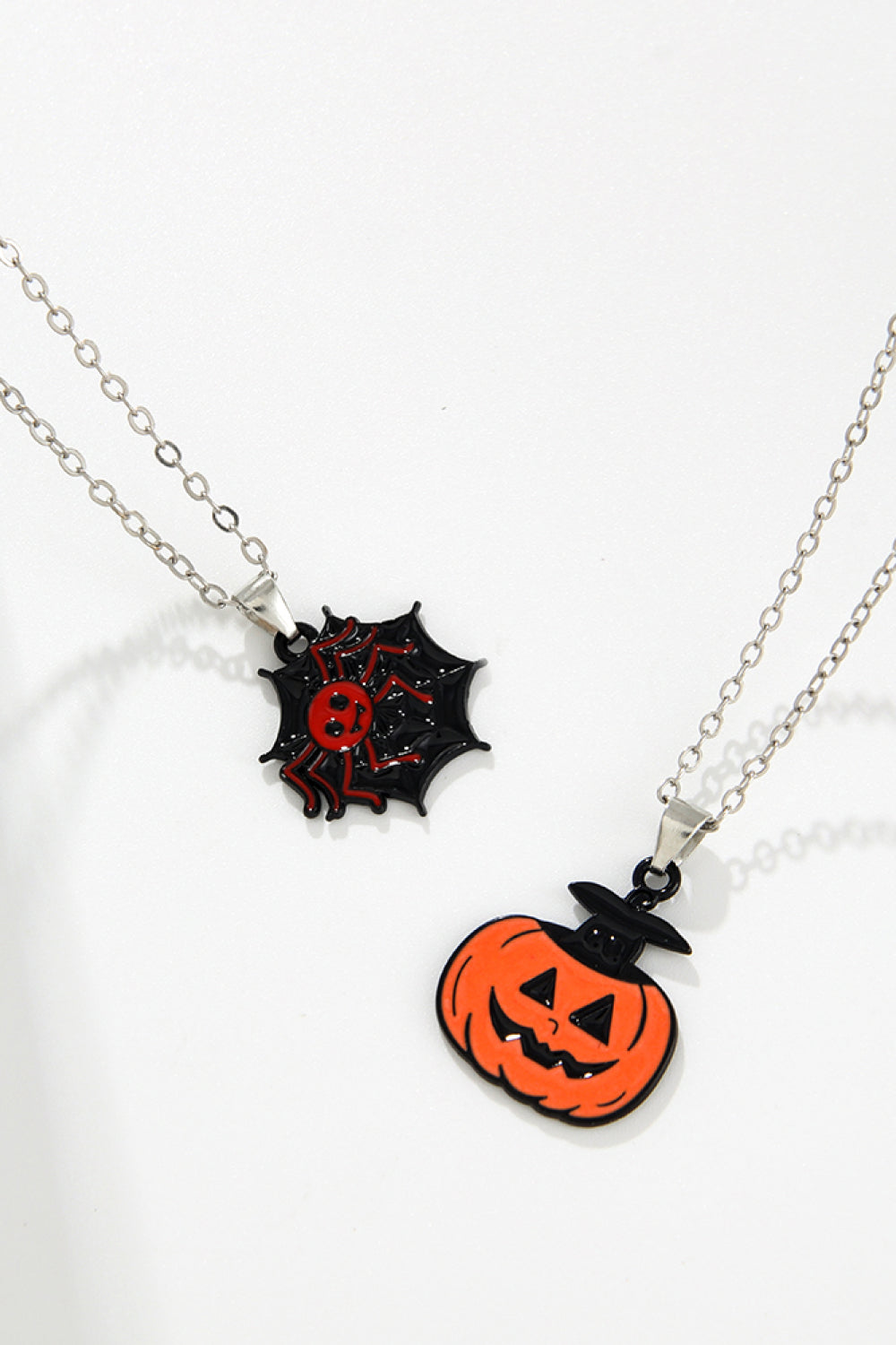 Spooky Season enamel pendant necklaces with spider web and jack-o-lantern charms.