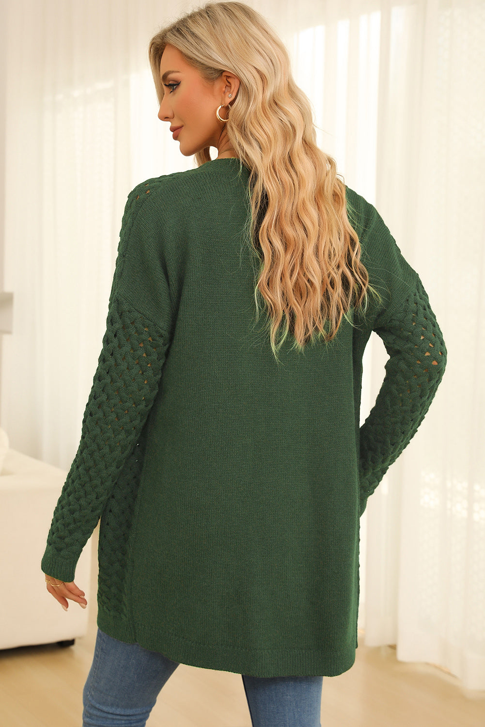 Dark green open-knit pocket cardigan with textured sleeves.