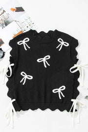 Black knit vest with white bow print, scalloped hem, and tie details.