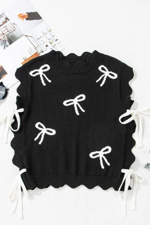 Black knit vest with white bow print, scalloped hem, and tie details.