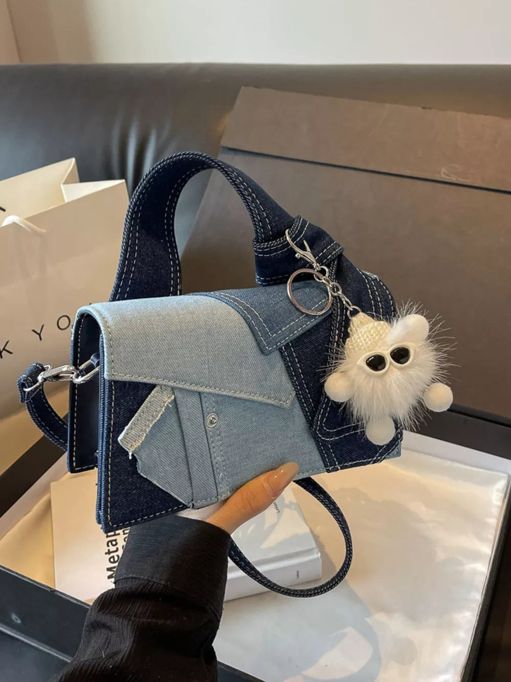 Artisanal mini denim crossbody bag with patchwork design and fuzzy charm.