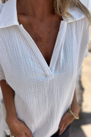 White textured cotton blouse with eyelet sleeves and V-neck.