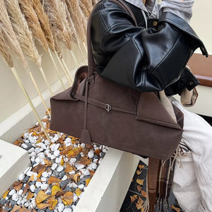 Brown suede tote handbag with decorative strap detail and top handles.