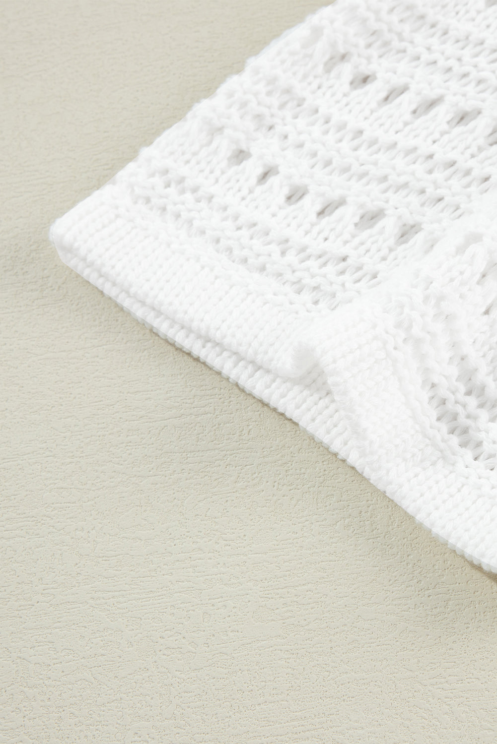 White open-knit acrylic cardigan with dolman sleeves and a textured pattern.