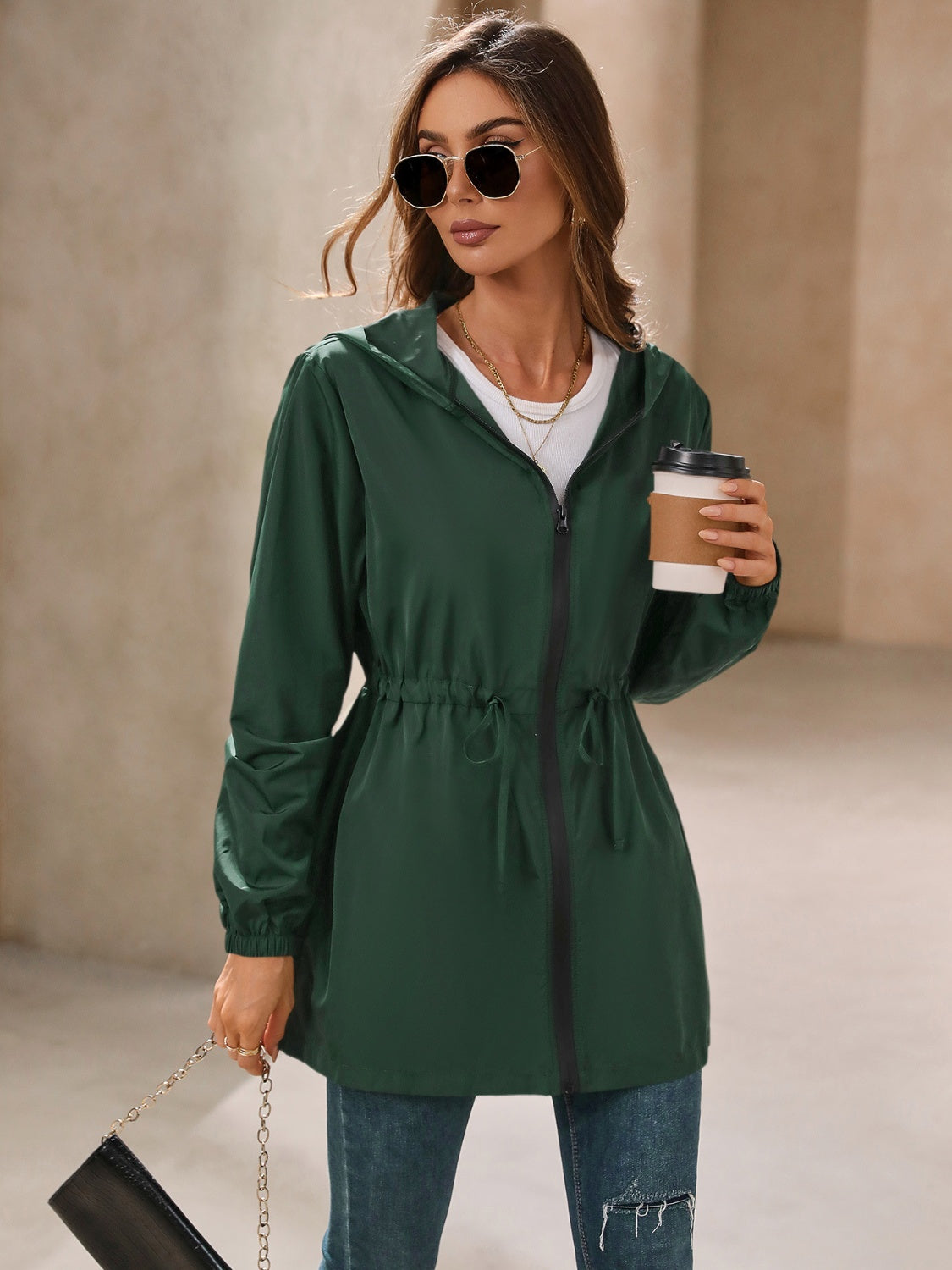 Dark green hooded jacket with cinched waistline and zip front, styled casually.