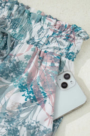 Botanical print maternity swimwear shorts with smocked waist and pockets holding a phone.