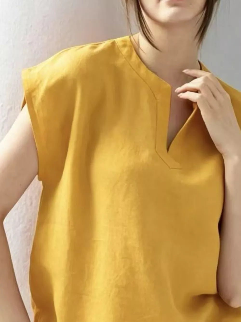 Yellow cap sleeve shirt with notched neckline and casual fit.