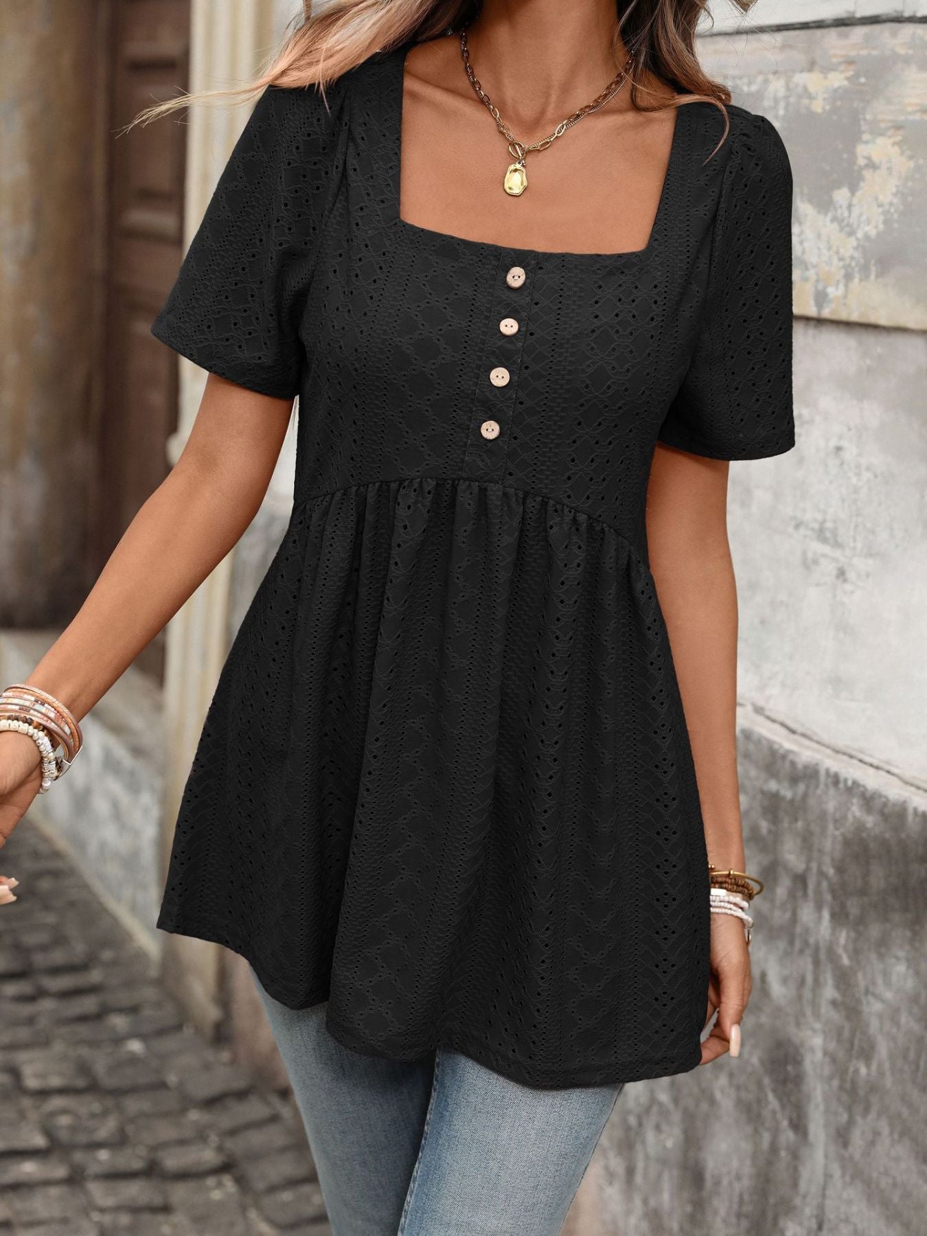 Black eyelet babydoll top with square neck, puff sleeves, and decorative buttons.