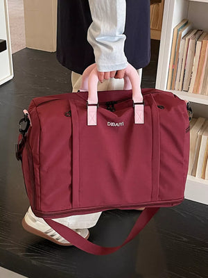 Burgundy nylon travel duffel bag with padded pink handles and detachable strap