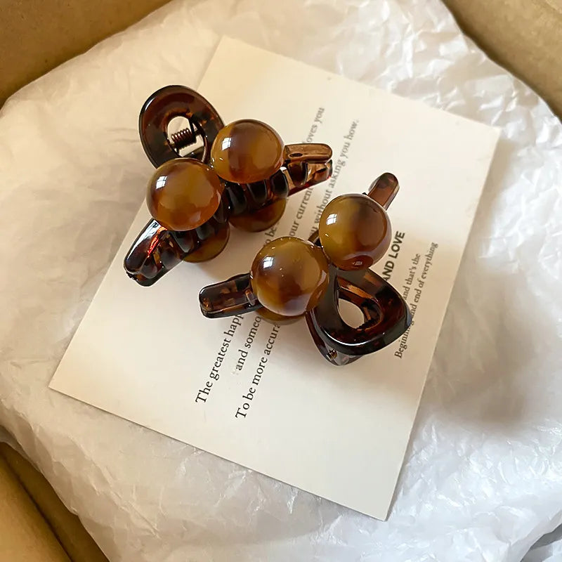 Brown resin orb hair claws with a marbled pattern.